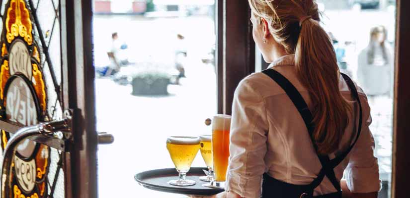 Bediening met een dienblad vol bier bij het glas-in-lood